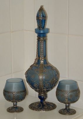Blue glass and metal decanter set
Decanter and four goblets. Unknown maker, no marks. Blue satin glass with applied metalwork. 
