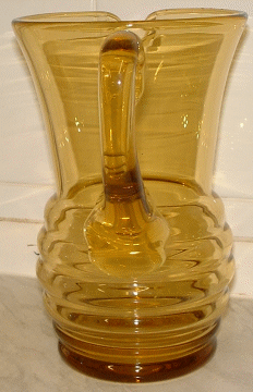 Seneca tall amber jug - view 3
Amber jug with beehive shaped lower half, has polished pontil and applied handle.  Now known to be Seneca Glass Company, of Morgantown, West Virginia pattern "Streamline", design Patent number "d 60637" from 1937. [Source: Mike (butchiedog) on the Glass Message Board]
Keywords: Seneca mouldblown USA