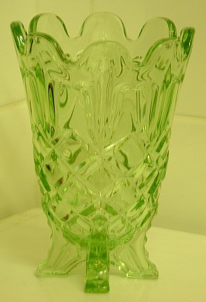 Sowerby uranium green pressed vase - side view
Pressed glass vase, clear green glass. No makers' marks. Made in a four part mould (four mould seams visible), stands on four squared off feet. Glows so I suspect it's uranium glass.  Now confirmed as Sowerby F 2583 vase. [Source: Glen Thistlewood on the [url=http://www.glassmessagesboard.com]Glass Message Board[/url]]
Keywords: uranium pressed Sowerby England